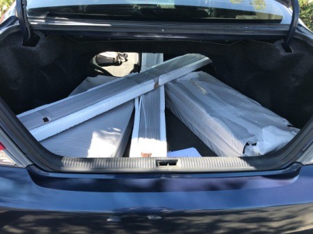 Shelving pieces removed from packaging and placed in a car's trunk.