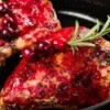 Berry glazed chicken with cranberry on rosemary garnish.