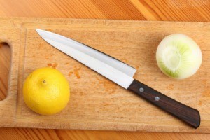 Lemon, onion and kitchen knife on a wooden board