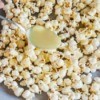 White chocolate being poured over popcorn.