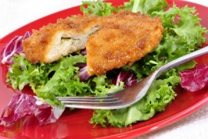 Stuffed, breaded chicken breast on a bed of lettuce.