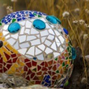 Mosaic covered bowling ball outside.