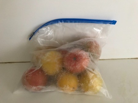 A ziptop bag of whole tomatoes to be frozen.