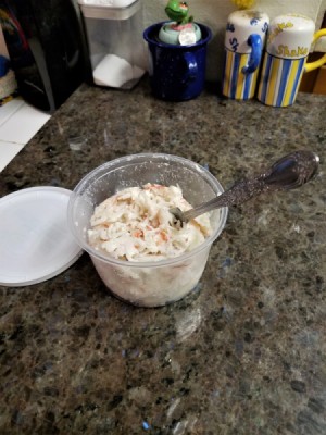 A container of seafood salad with a fork in it.