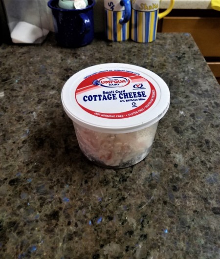 A container of seafood salad with cottage cheese lid.