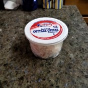 A container of seafood salad with cottage cheese lid.