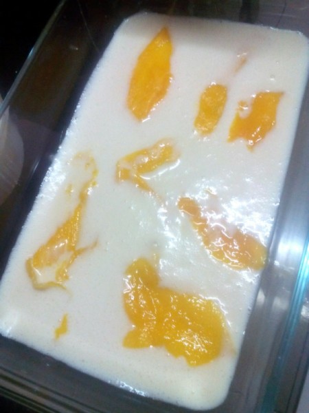 Mango strips on milk in pan
