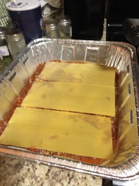 Lasagna on sauce in pan