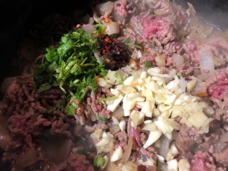 adding ground beef and cilantro to onions