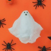 Gauze ghost on orange surrounded by spiders.