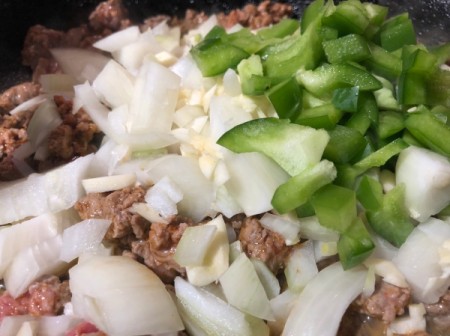 adding onions, green peppers and garlic to pan