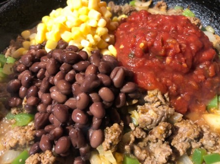 adding beans, corn and sauce added to pan