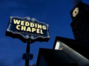 A neon Graceland wedding chapel sign next to a chapel.