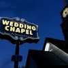 A neon Graceland wedding chapel sign next to a chapel.