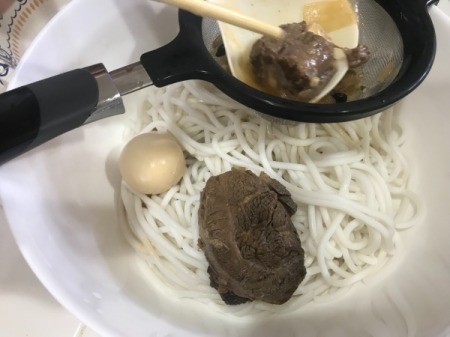 Leftover broth being strained before being added to a bowl.