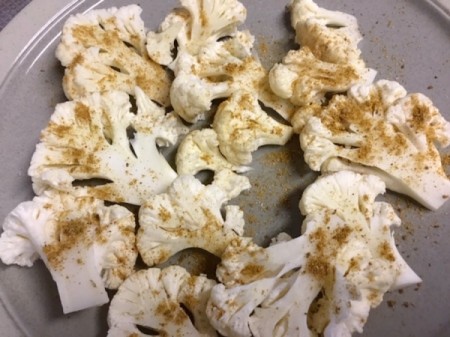Raw Cauliflower slices sprinkled with spices