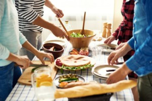 A dinner party with many young adults serving from a counter.