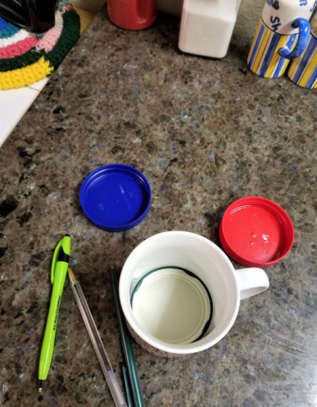 A lid inside a mug that will be used to store pens.