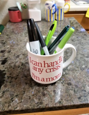 A mug holding pens on a countertop.