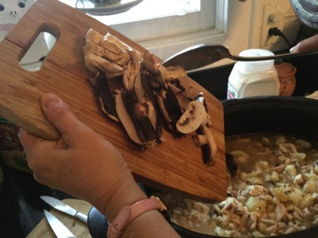 adding sliced mushrooms to pot