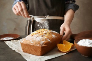 sprinkling powdered sugar on a loaf cake