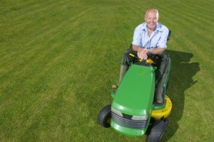 man sitting on a green and yellow riding mower