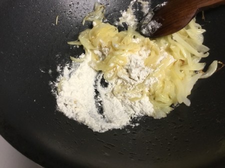 adding flour to sauteed onions
