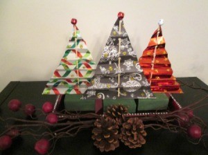 Making Accordion Christmas Trees - three finished trees with a tiny ball ornament on top, and pine cones and other decorations in front