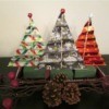 Making Accordion Christmas Trees - three finished trees with a tiny ball ornament on top, and pine cones and other decorations in front
