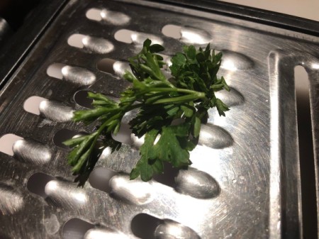 Herbs being pulled through a grater to separate the leaves from the stem.