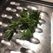 Herbs being pulled through a grater to separate the leaves from the stem.