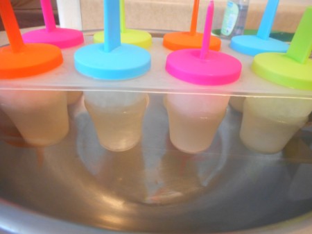 frozen Lemon Lime Popsicle molds in warm water