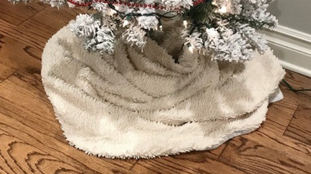 A blanket being used as a Christmas tree skirt.