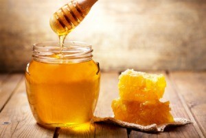 Jar of honey next to pieces of honeycomb