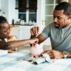 Father and daughter putting money in a piggy bank.