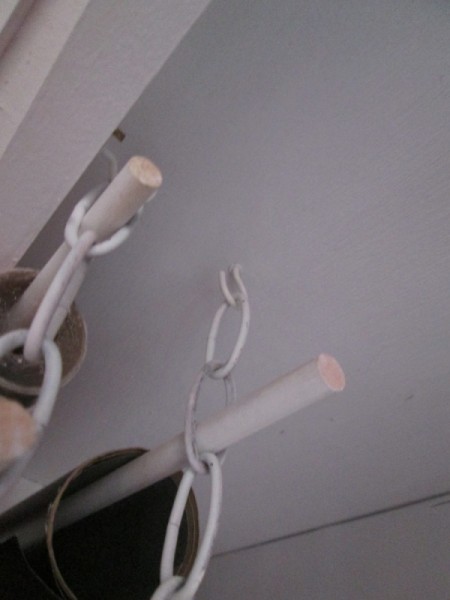 A rod being suspended by a chain under a shelf.