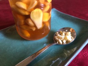 A spoonful of minced garlic next to a mixture of garlic and honey.