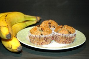 chocolate chip muffins on plate next to bunch of bananas