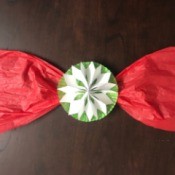 Snowflake Bow for Oversize Gift - red tissue paper bow with a paper snowflake in the center mounted to a cupcake liner