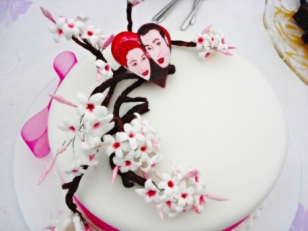 A wedding cake with faces and delicate flowers.