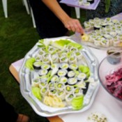 A potluck table at a wedding with rolled sushi and other foods.
