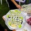 A potluck table at a wedding with rolled sushi and other foods.