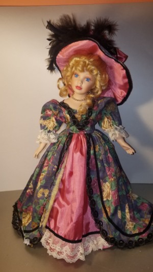 Identifying a Porcelain Doll - doll wearing a long floral dress with a dark pink under skirt and matching hat