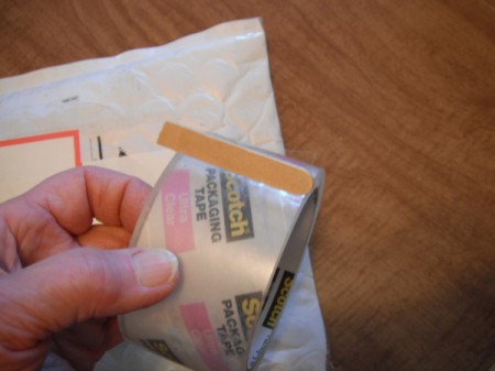 Securing the End of Packaging Tape - Popsicle stick marking the end of a roll of packing tape.