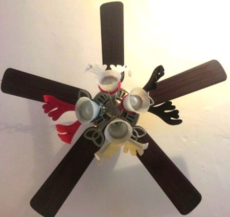 A ceiling fan decorated with reindeer antlers.