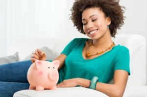 Woman putting money in a piggy bank.