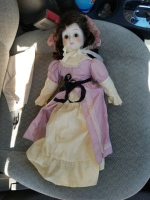 Identifying a Porcelain Doll - doll wearing a bonnet and an ecru dress with a pink over skirt