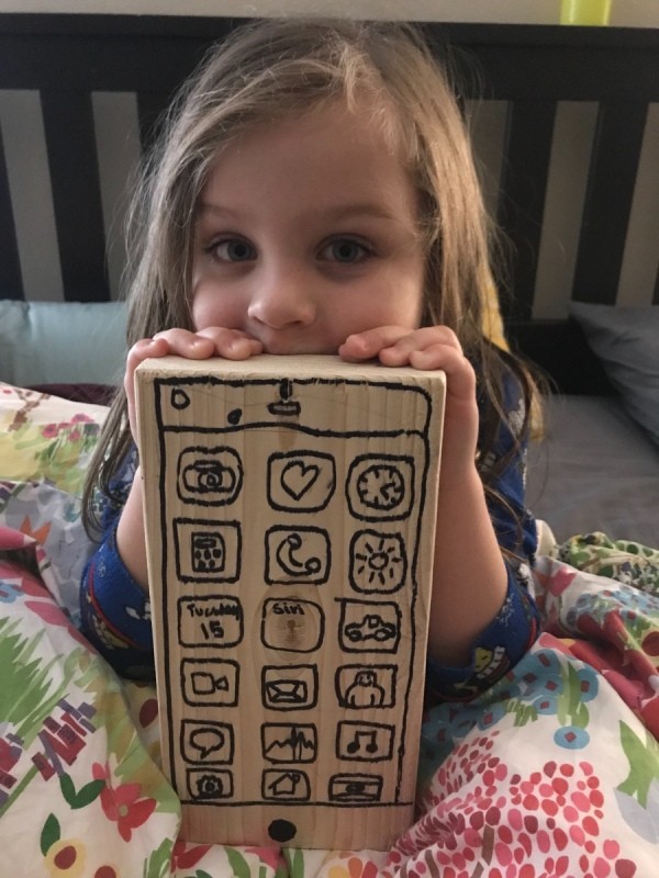 A play cellphone made from wood with drawn buttons.