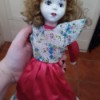 Age of a Porcelain Doll - doll wearing dress with floral bodice and red skirt