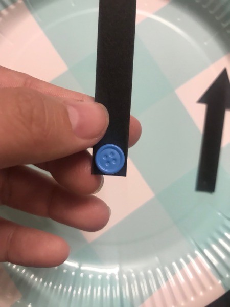 Paper Plate Clock - blue button shaped fastener through one arrow